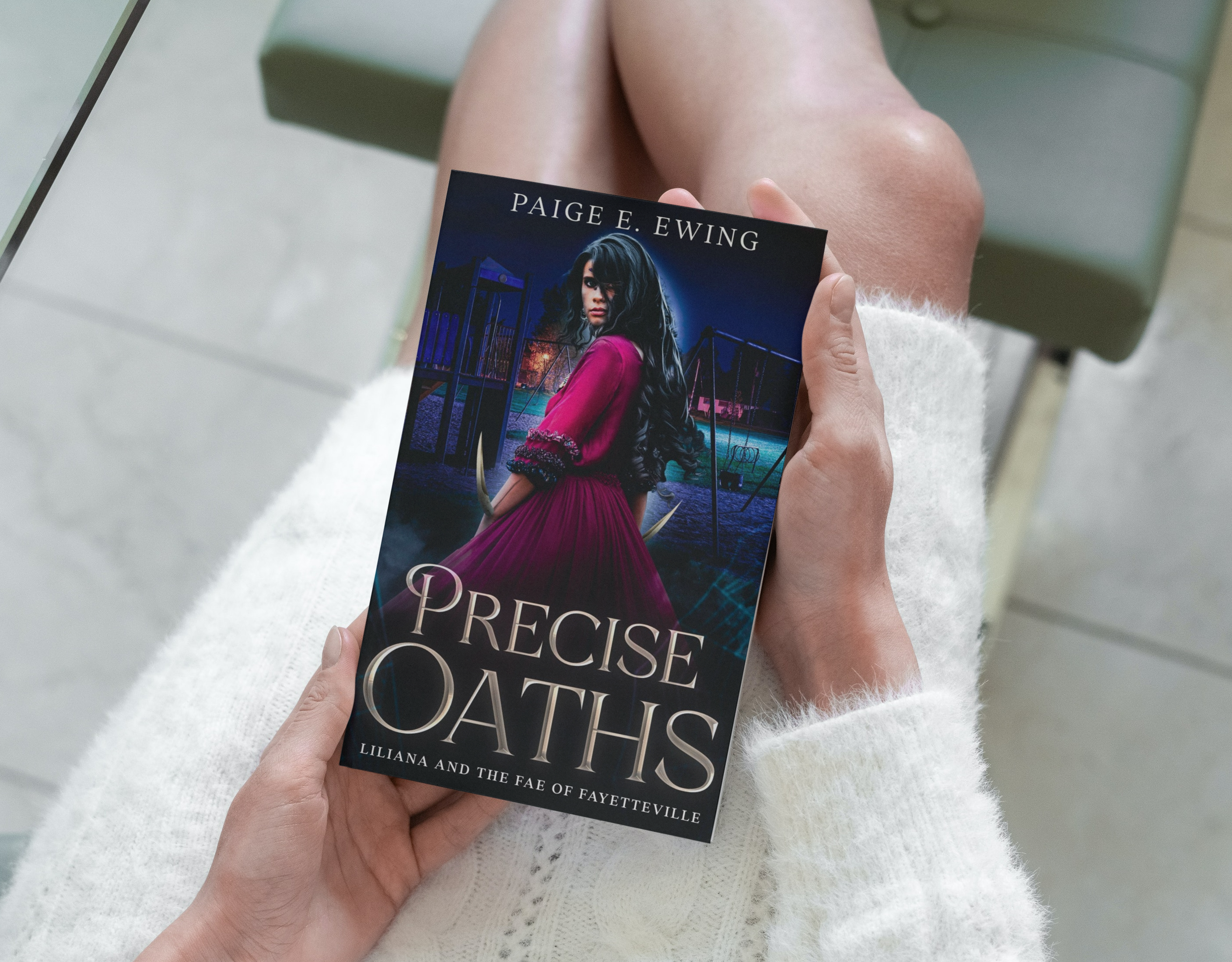 Book - Precise Oaths - in the hands of a woman wearing a white sweater dress.